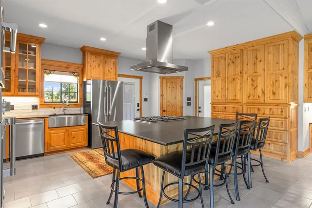 a kitchen with stainless steel appliances granite countertop a table chairs and a refrigerator