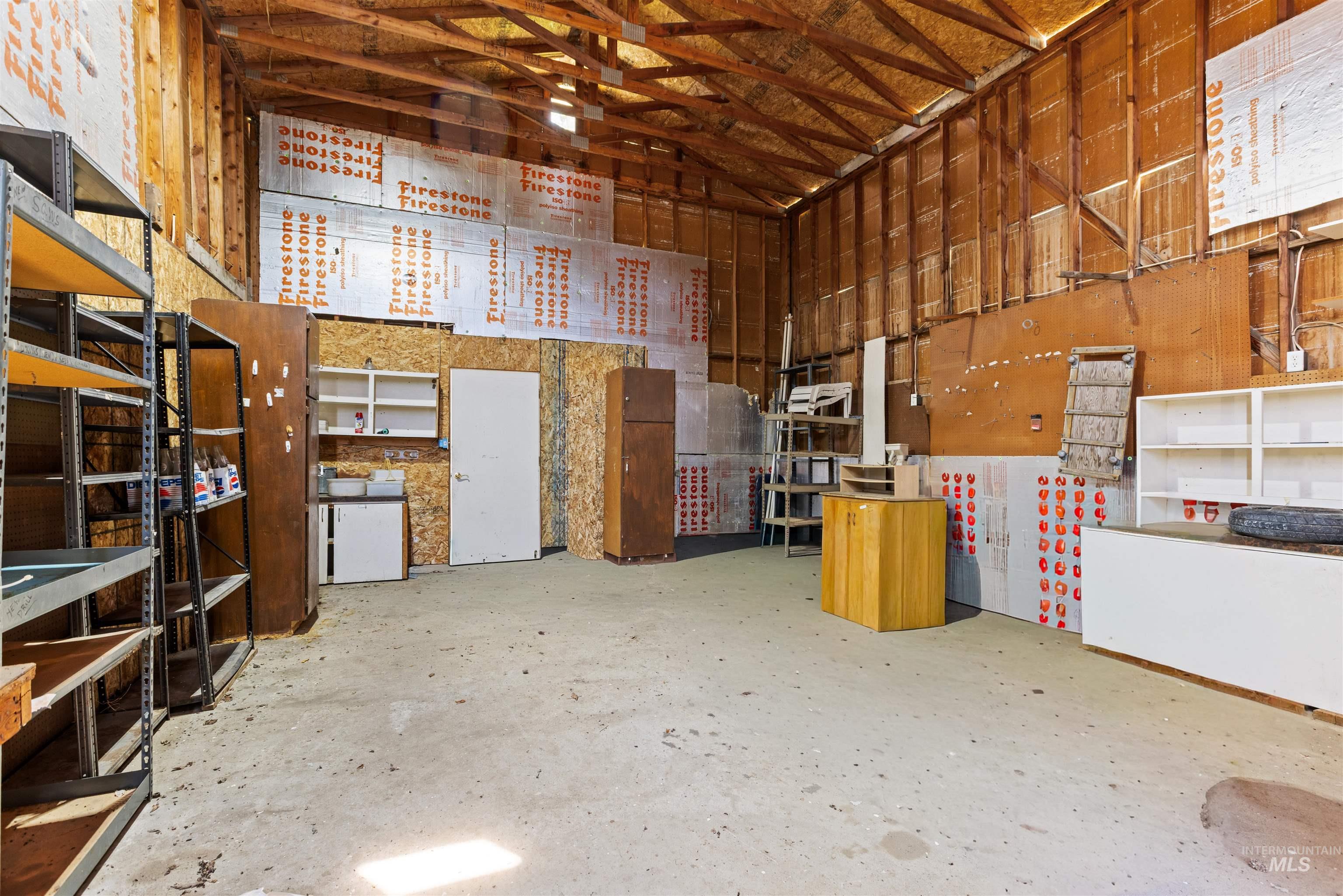 12184 Hill Road Payette, ID 83661 - Photo 29 of 35 Expansive interior space featuring exposed wood beam ceiling, concrete flooring, and extensive wall shelving