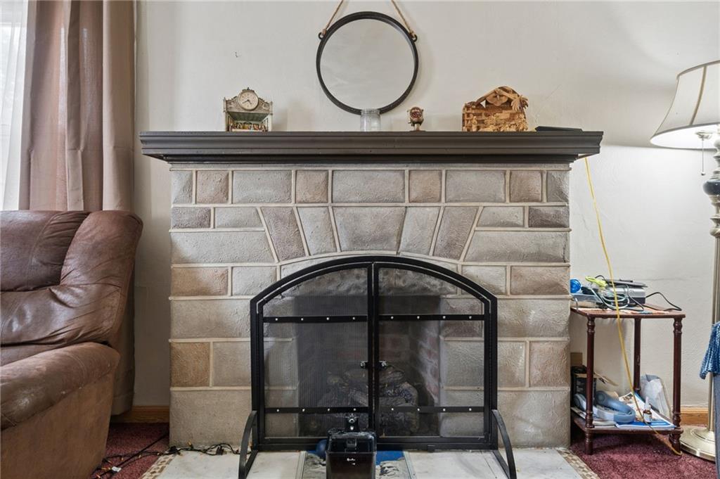 2106 Lindsay Road Pittsburgh, PA 15221 - Photo 16 of 36 The living room features a stone fireplace, crowned by a thick, rustic woo mantle that serves as the warm focal point of the room.
