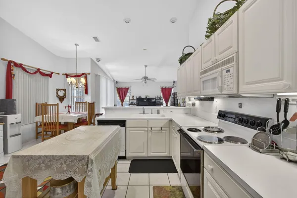 a living room with furniture kitchen view and a chandelier