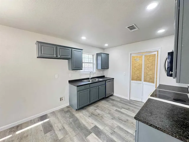 a large kitchen with granite countertop a sink and a stove top oven