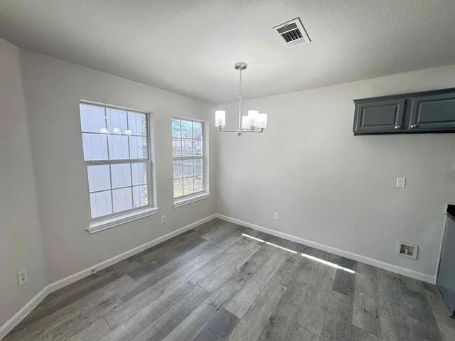 an empty room with chandelier fan and windows