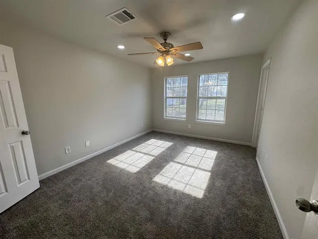 an empty room with windows and ceiling fan