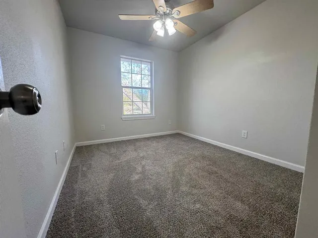 an empty room with windows and fan