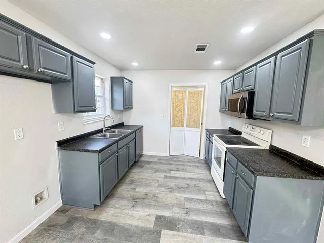 a kitchen with stainless steel appliances granite countertop a stove top oven a sink dishwasher a refrigerator and a microwave