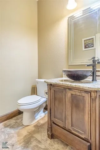 a bathroom with a granite countertop toilet and a sink