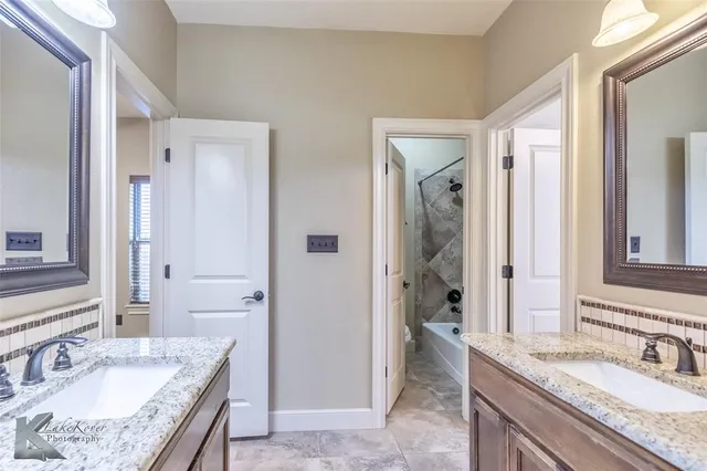 a bathroom with a granite countertop tub sink and mirror