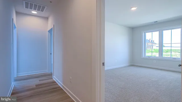 a view of hallway with window and wooden floor