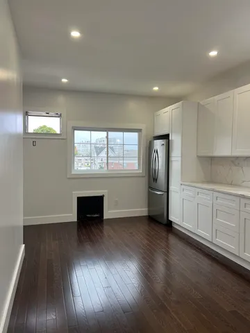 an empty room with wooden floor cabinet and windows