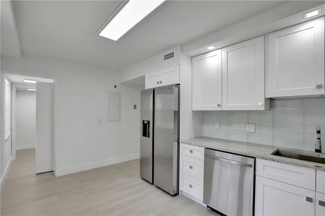 a kitchen with stainless steel appliances granite countertop white cabinets and refrigerator