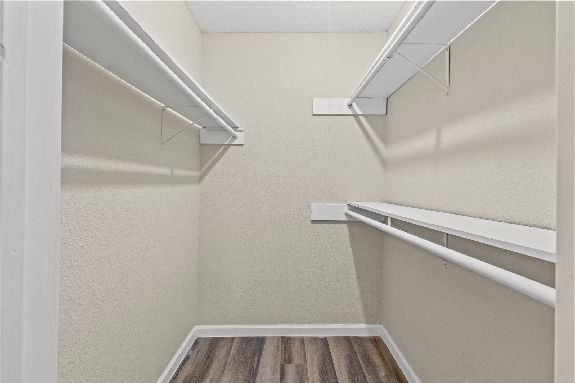 5026 Fitzwater Drive Spring, TX 77373 - Photo 13 of 14 In the primary is a spacious walk-in closet with neutral walls, featuring multiple shelves and hanging rods for ample storage.
