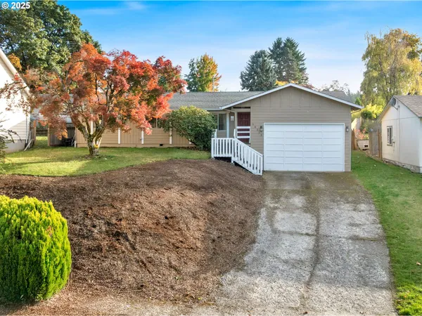 a view of a house with a yard and large tree