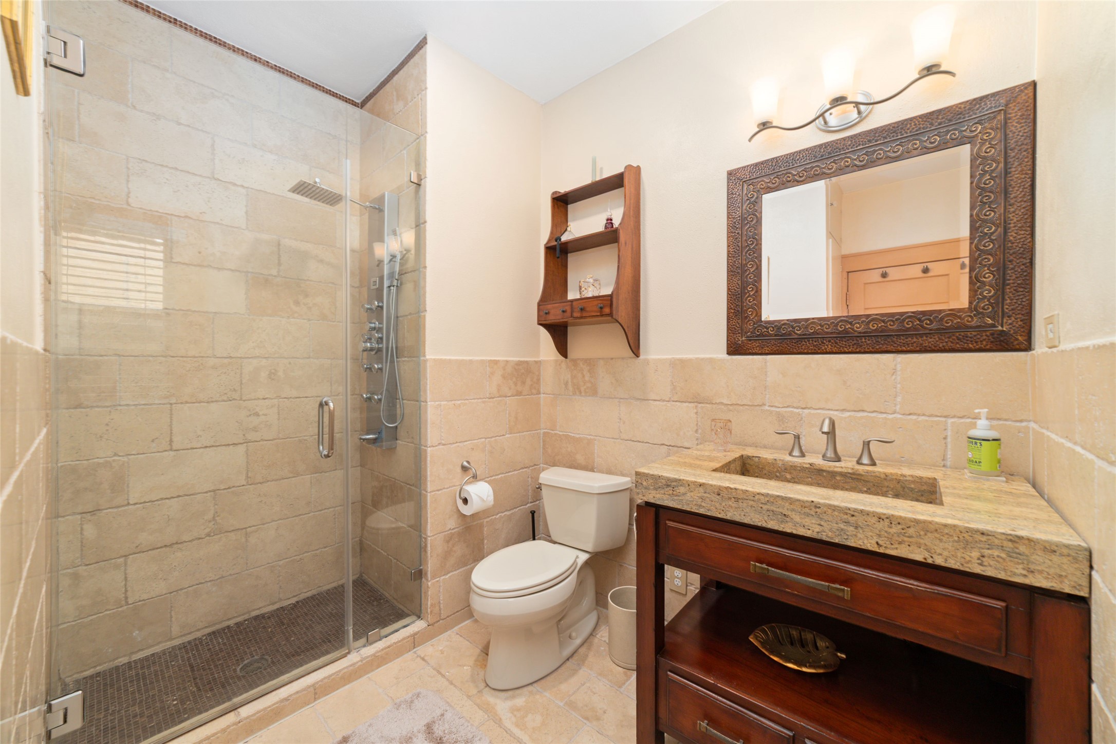 1613 California Street Houston, TX 77006 - Photo 29 of 50 The primary bath is finished in imported Egyptian travertine and anchored by a custom stone vanity with an integrated stone sink. A frameless glass shower and warm natural materials create a retreat that feels both timeless and inviting.