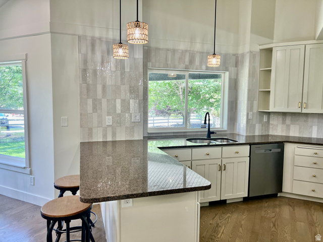812 East Bates Cyn Road Tooele, UT 84074 - Photo 26 of 144 Kitchen featuring a breakfast bar with stone countertop, stainless steel sink with matte black faucet, full-height tile backsplash, white cabinetry, and wood-finish flooring