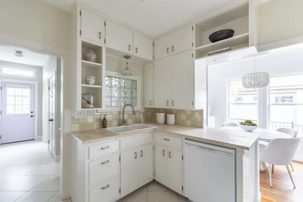 a kitchen with a sink dishwasher a stove and white cabinets