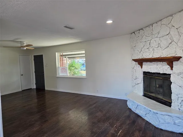 an empty room with wooden floor fireplace and windows