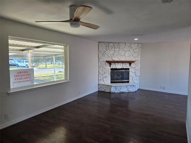 a view of an empty room with wooden floor fireplace and a window