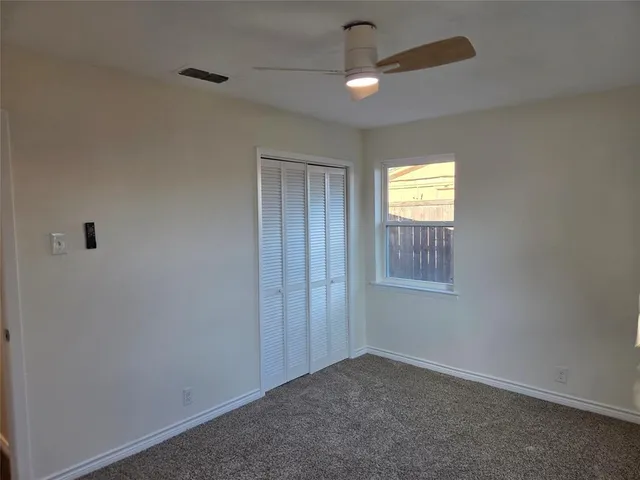 an empty room with window and chandelier fan