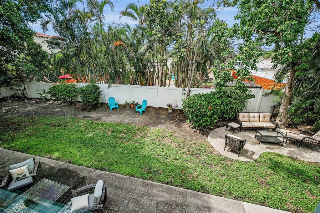 9945 47th Avenue North, Unit 210 St. Petersburg, FL 33708 - Photo 45 of 78 a backyard of a house with table and chairs plants and large trees