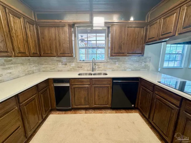 a kitchen with granite countertop a sink dishwasher stove and cabinets