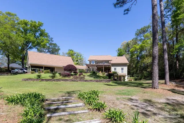 a view of a white house with a yard and potted plants