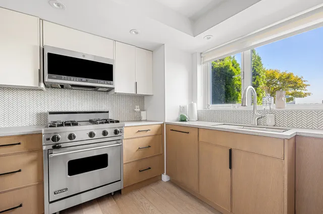 a kitchen with stainless steel appliances granite countertop a stove a sink dishwasher and a refrigerator with wooden floor