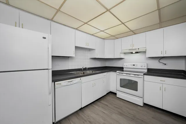 a kitchen with granite countertop white cabinets and white appliances