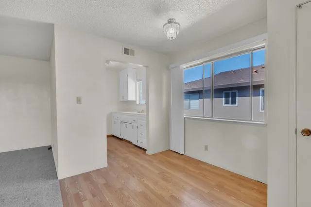 a view of a livingroom with wooden floor and kitchen space