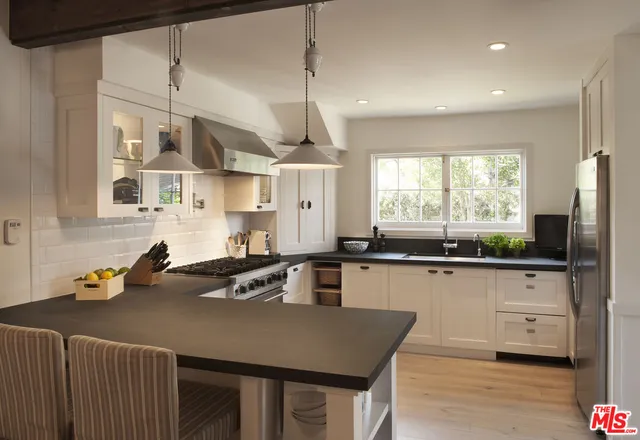 a kitchen with granite countertop a sink a counter space appliances and cabinets