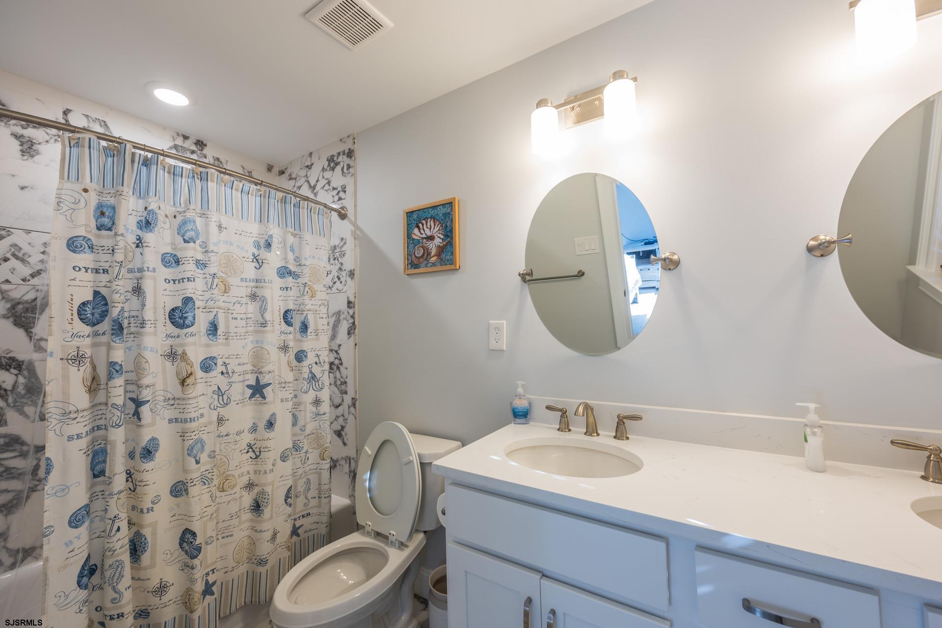 910 Ocean Avenue, Unit C Ocean City, NJ 08226 - Photo 31 of 36 a bathroom with a granite countertop toilet a sink a mirror a and a shower curtain