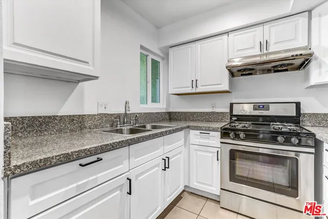 a kitchen with granite countertop white cabinets and a stove top oven
