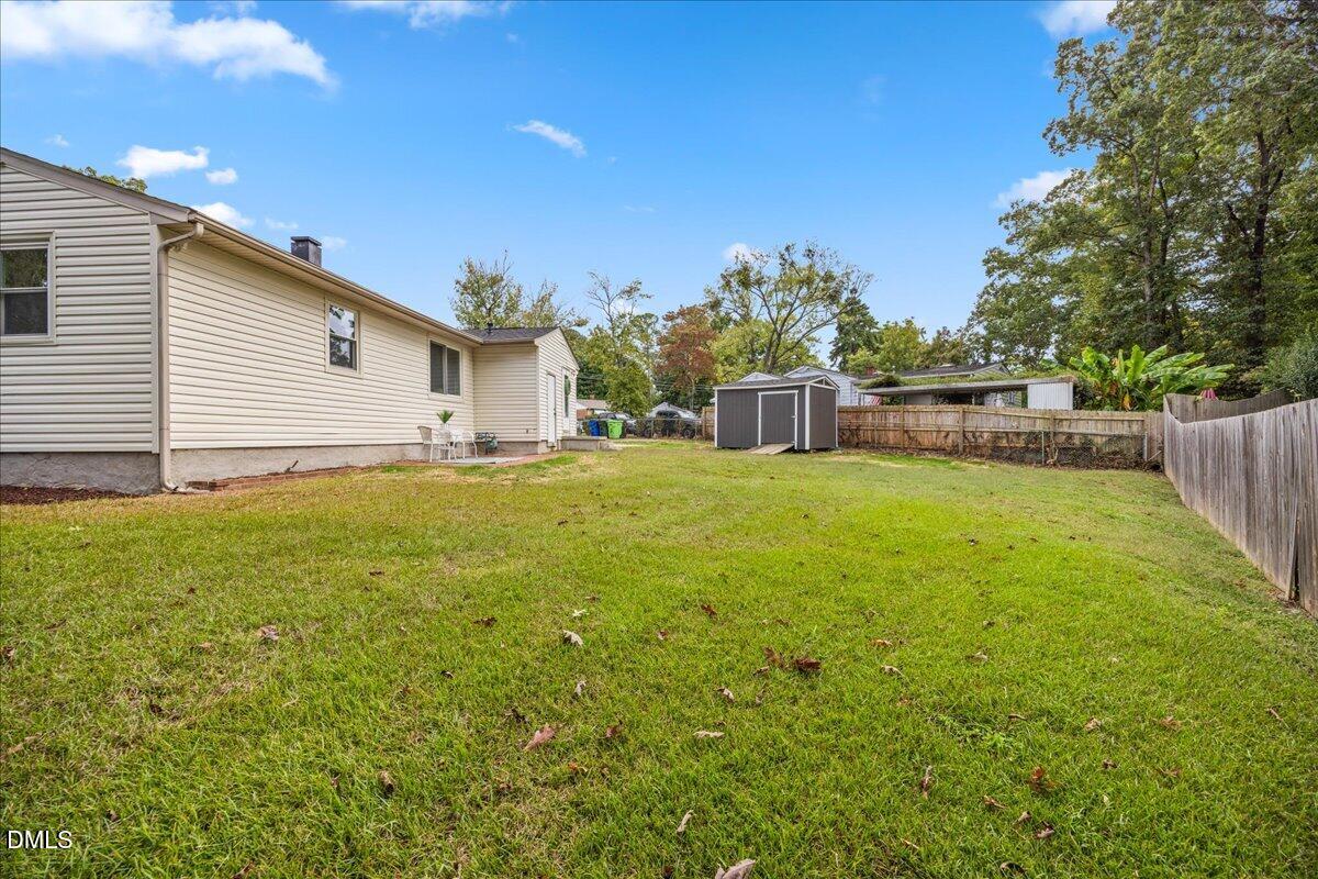 3437 Apache Drive Raleigh, NC 27609 - Photo 29 of 40 Expansive backyard featuring a manicured lawn, a partial fence, and a storage shed