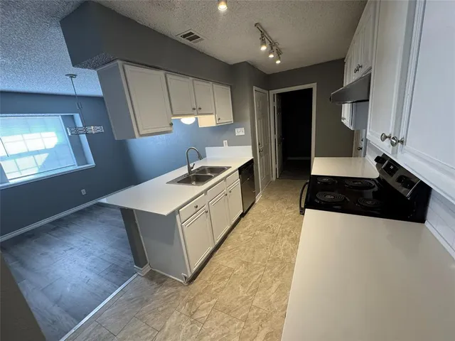 a kitchen with stainless steel appliances a sink a stove a refrigerator and cabinets