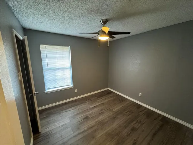 an empty room with wooden floor fan and window