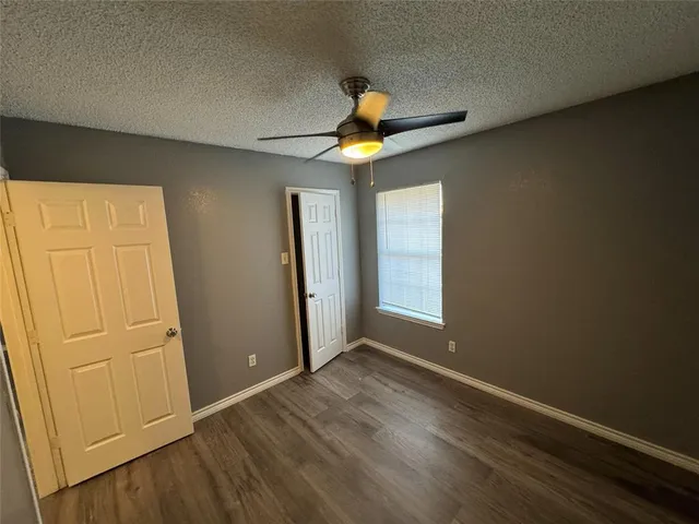 an empty room with wooden floor closet and windows