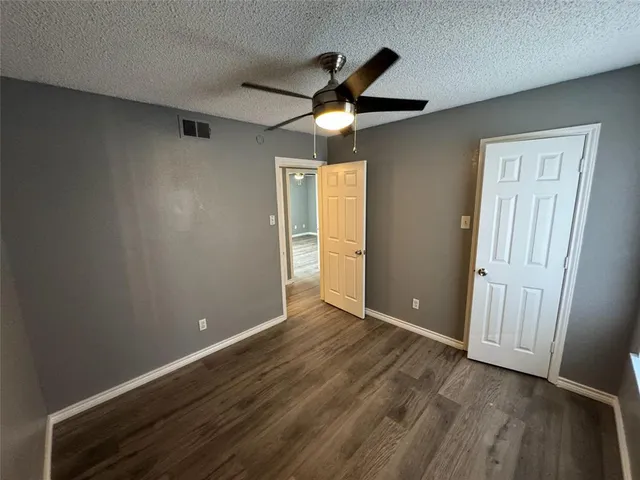 an empty room with wooden floor cabinet and a ceiling fan