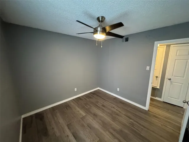 an empty room with wooden floor fan and windows