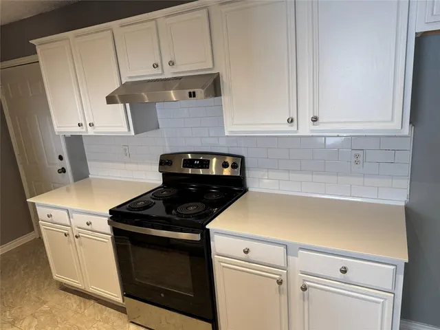 a kitchen with white cabinets and black appliances