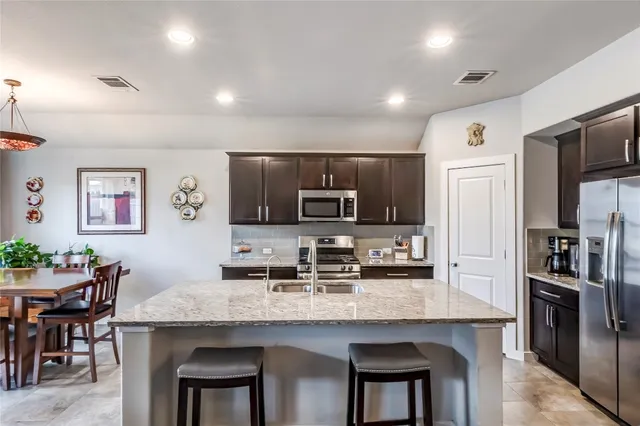 a kitchen with granite countertop a refrigerator and microwave
