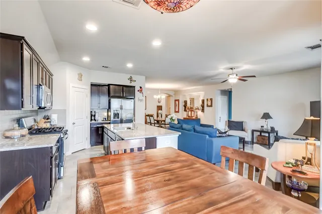 a kitchen with a stove a sink a counter top space and living room view