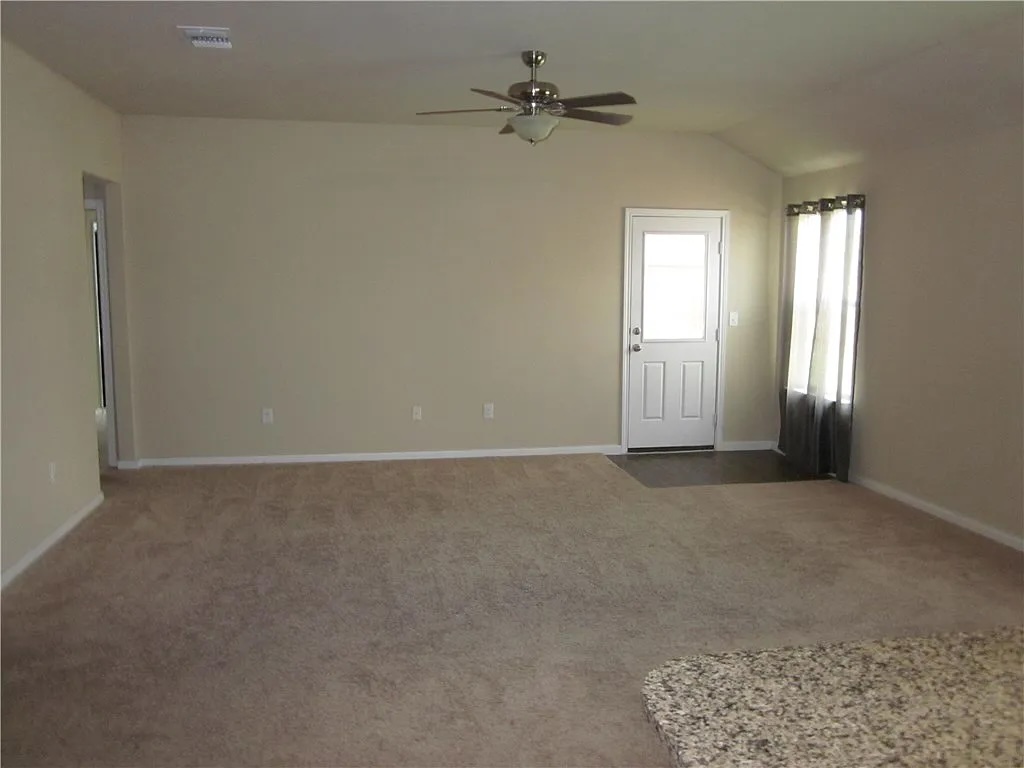 541 Alpha Kyle, TX 78640 - Photo 2 of 9 A living area with neutral carpet and vaulted ceilings, ready for personal touches.
