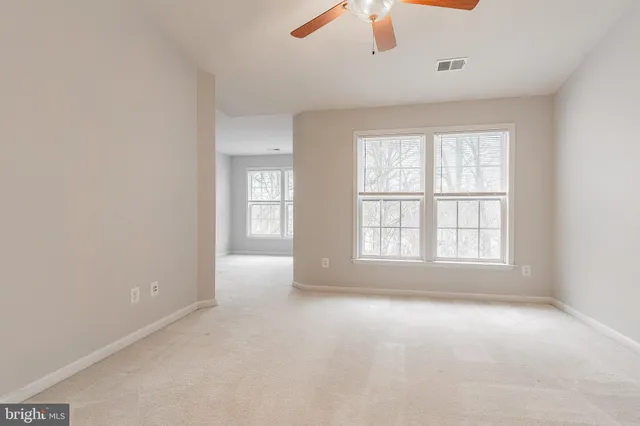 a view of an empty room with a chandelier fan