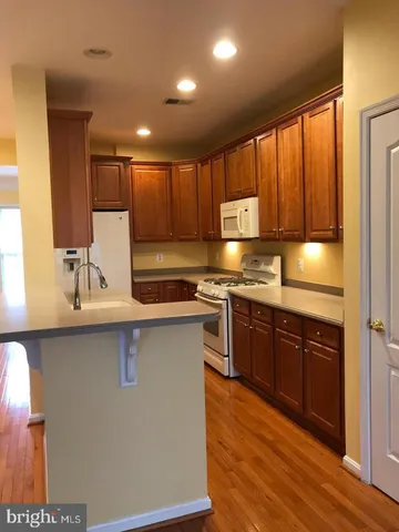 a kitchen with stainless steel appliances granite countertop wooden cabinets a stove top oven a sink and dishwasher with wooden floor