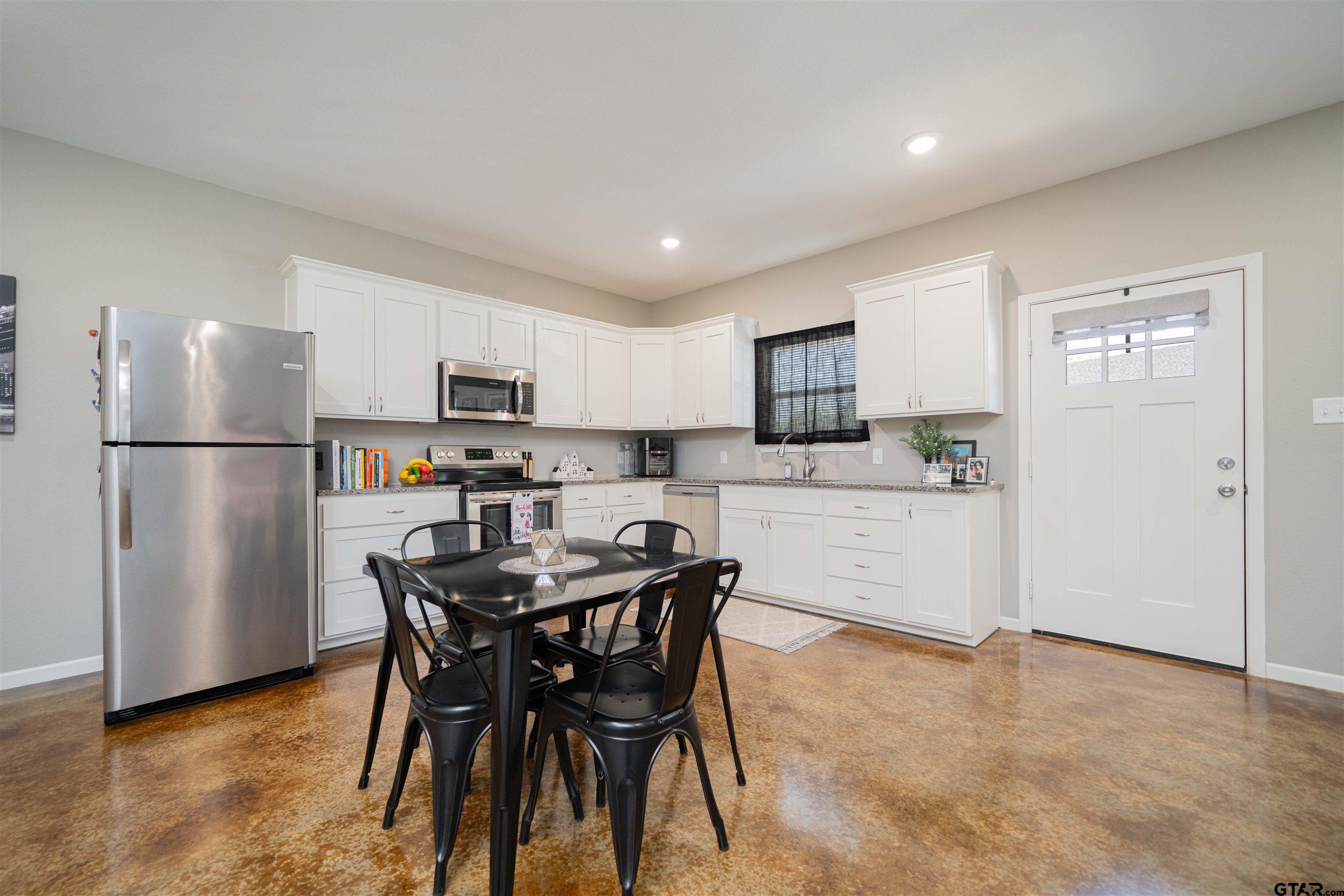 128 Loye Lane Hawkins, TX 75765 - Photo 9 of 25 a kitchen with stainless steel appliances a refrigerator a stove a microwave oven a sink a dining table and chairs