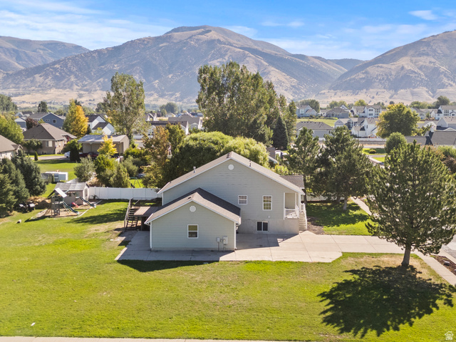 695 3480 South Logan, UT 84321 - Photo 17 of 20 Expansive green lawn, concrete patio, mature trees, and mountain backdrop