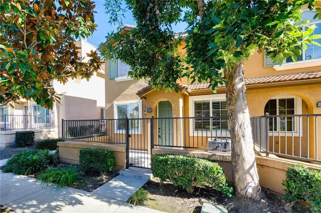 a view of a white house with a large tree and wooden fence