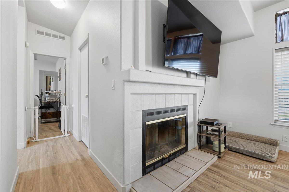 545 South Conover Street Eagle, ID 83616 - Photo 15 of 39 Living room featuring a tiled fireplace, light wood-style flooring, and lofted ceiling
