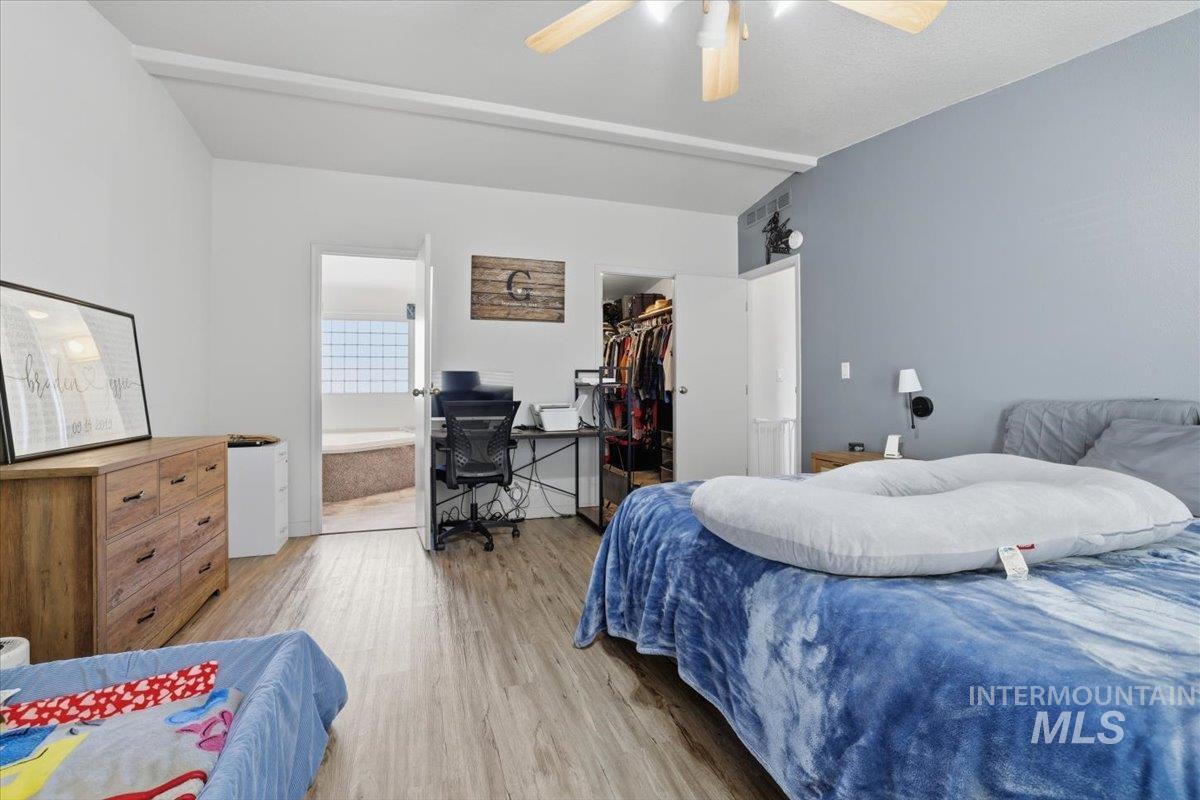 545 South Conover Street Eagle, ID 83616 - Photo 18 of 39 Bedroom featuring wood finished floors, a spacious closet, an office area, ensuite bath, and a ceiling fan