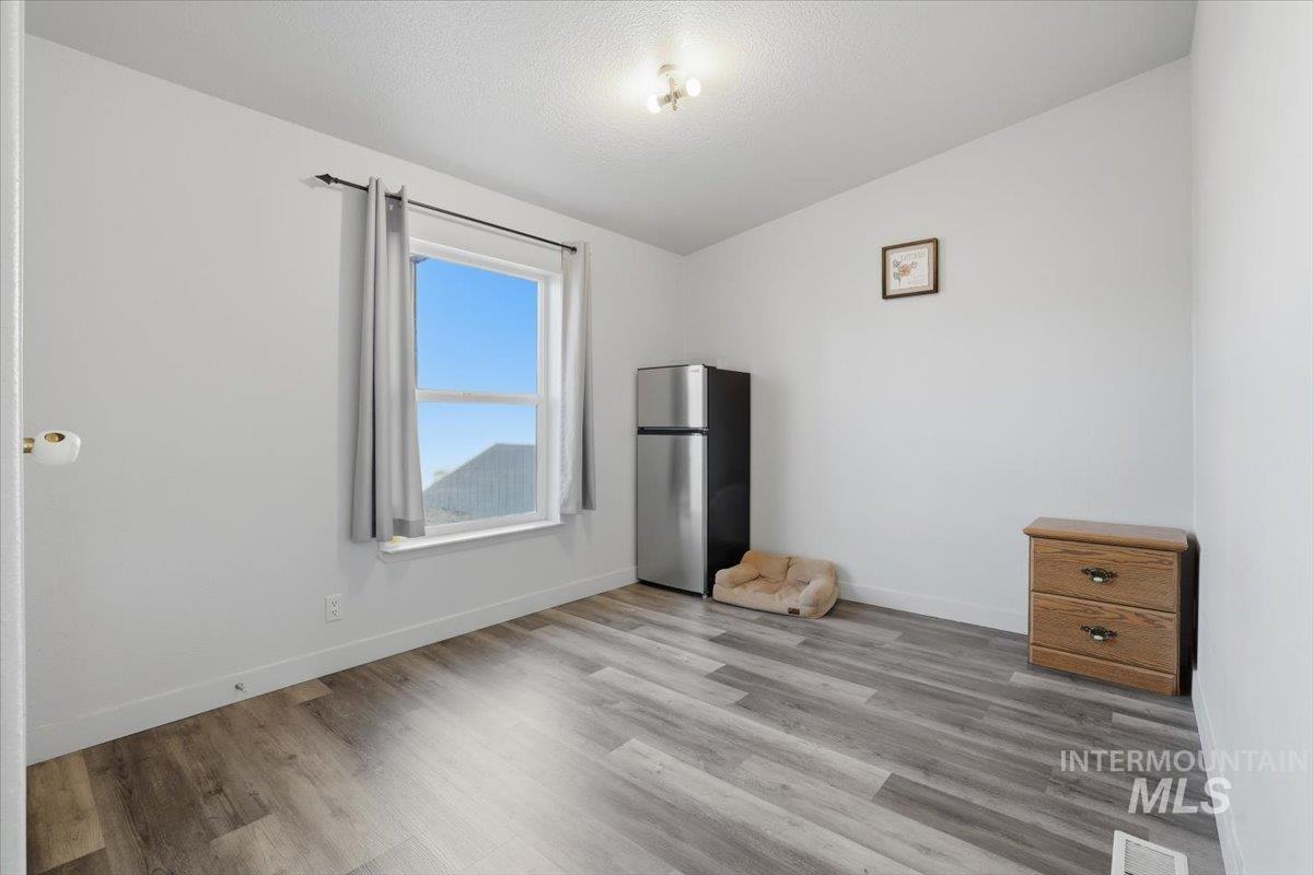 545 South Conover Street Eagle, ID 83616 - Photo 25 of 39 Unfurnished bedroom with freestanding refrigerator, lofted ceiling, wood finished floors, and a textured ceiling