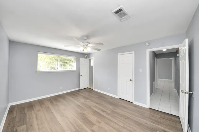 a view of an empty room with chandelier fan and window